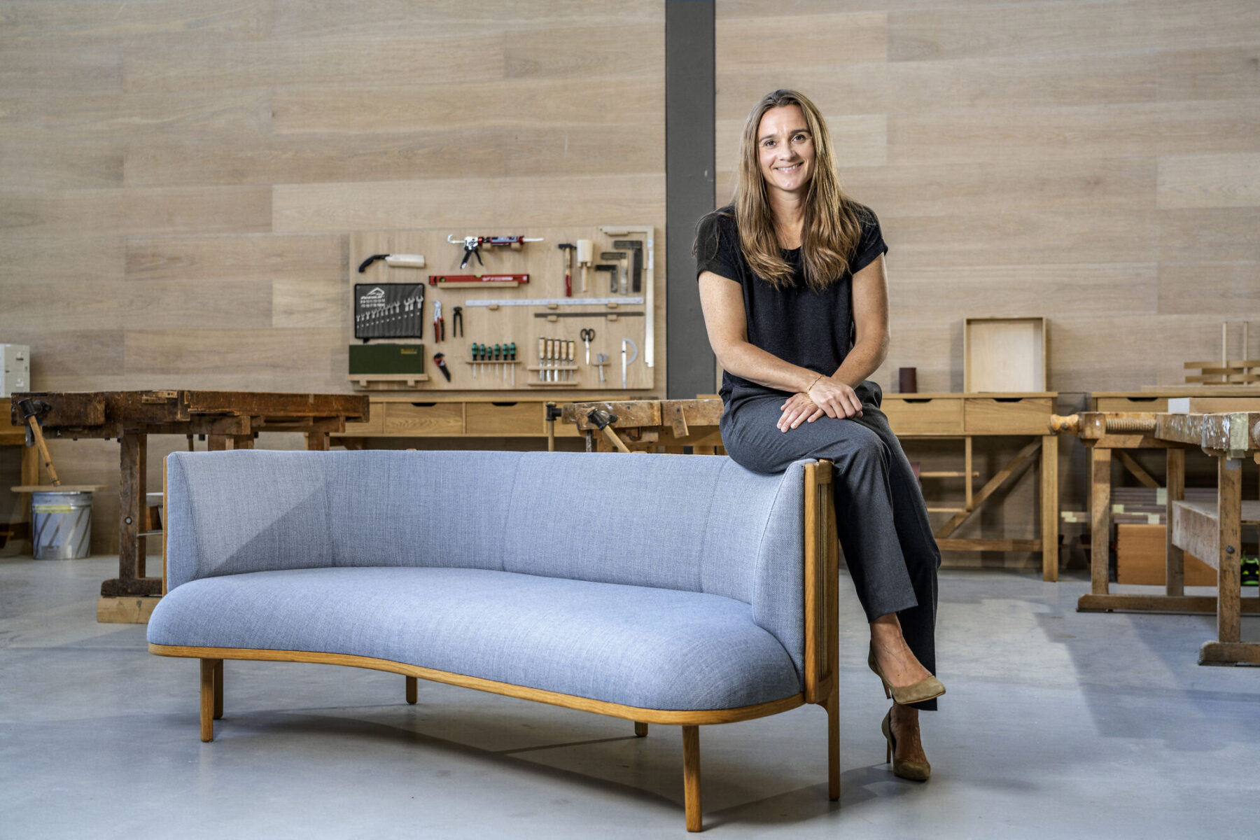 自身の代表作《Sideways Sofa》に腰掛けるリッケ・フロスト。人と人の自然な会話を生むデザインの思想を体現。